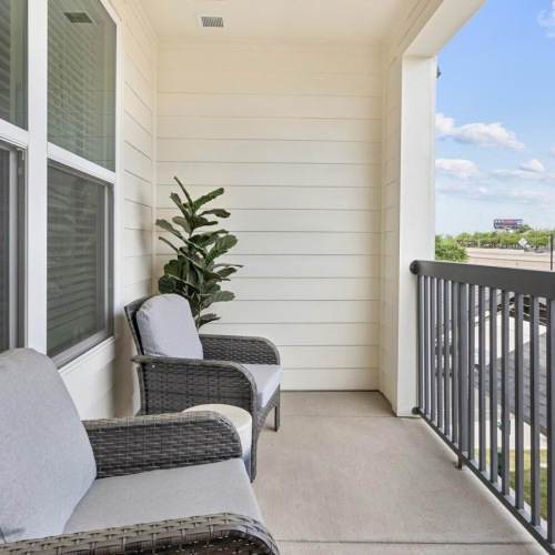 a patio with chairs and a railing